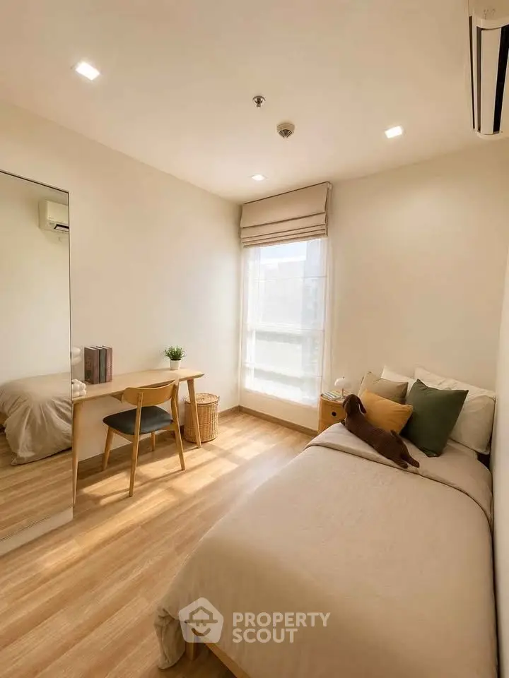 Cozy bedroom with natural light, wooden flooring, and minimalist decor for a serene living experience.