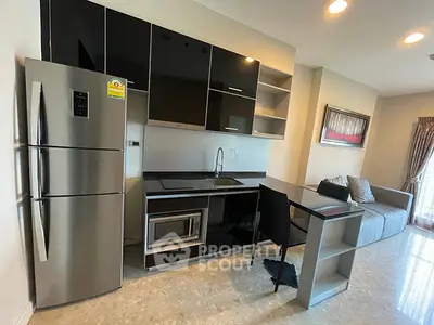 Modern kitchen with sleek black cabinets and stainless steel appliances in open layout apartment.