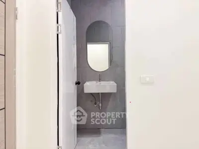 Modern minimalist bathroom with sleek oval mirror and compact sink