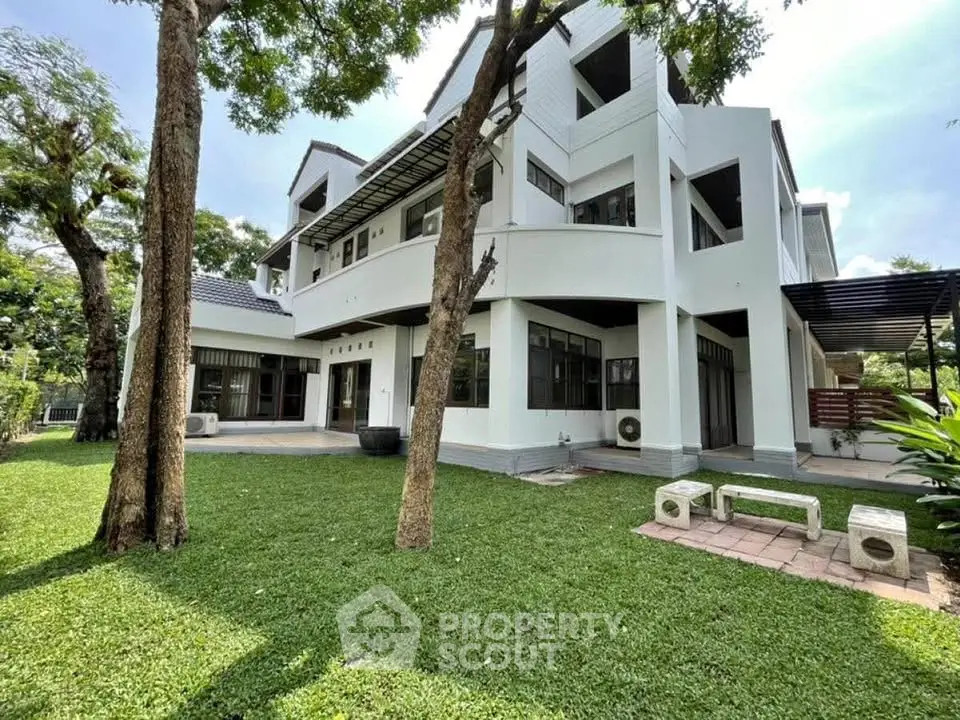 Stunning modern white house with lush green lawn and outdoor seating area.
