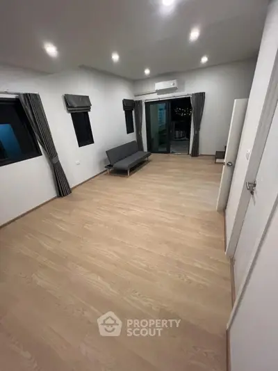 Spacious modern living room with wooden flooring and balcony access