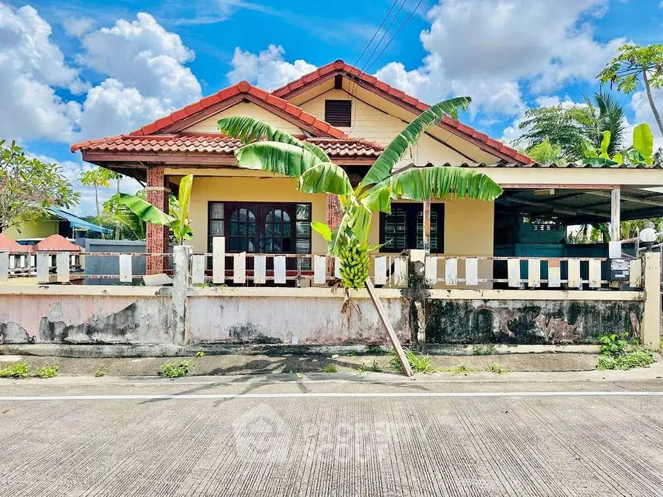 Charming single-story house with red roof and tropical garden in a serene neighborhood.