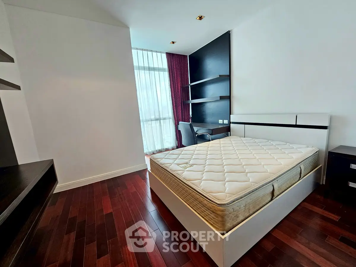 Spacious bedroom with hardwood floors and modern furnishings in a luxury apartment.