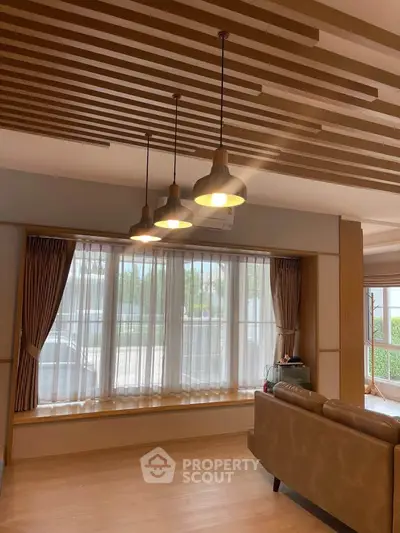 Modern living room with stylish lighting and large windows offering natural light.