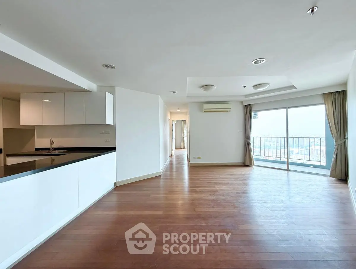 Spacious open-plan living room with hardwood floors and balcony view