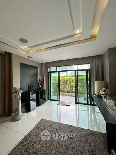 Spacious living room with modern decor and large glass doors leading to a lush garden view.