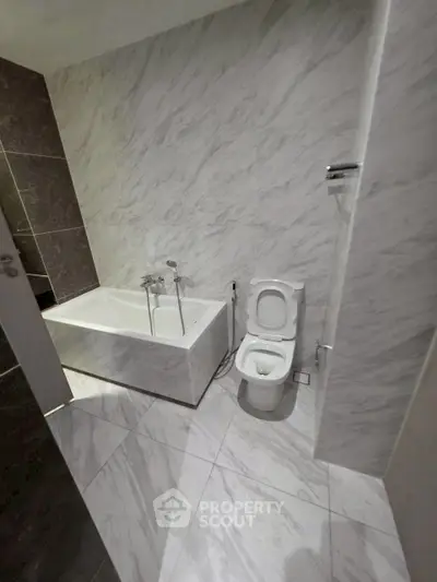 Modern bathroom with marble tiles and bathtub in a sleek design.