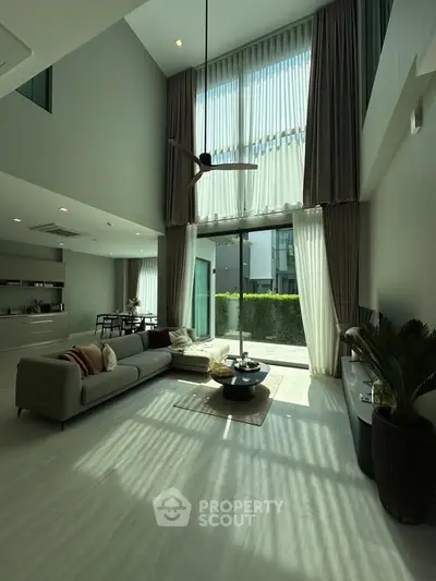 Luxurious modern living room with high ceilings and large windows offering abundant natural light.