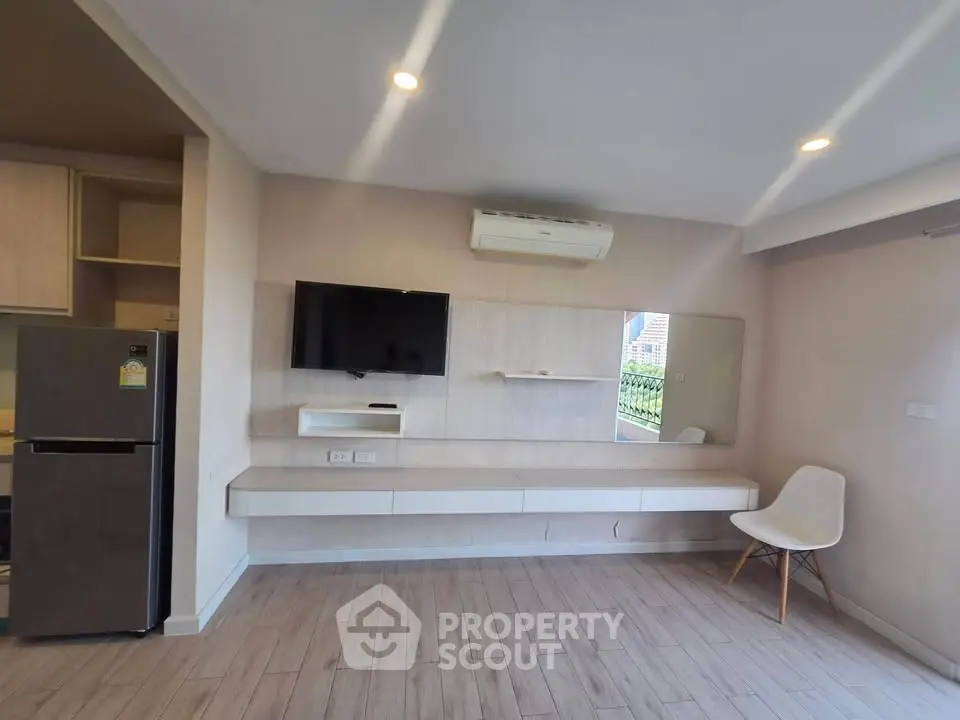 Modern living room with sleek design, featuring wall-mounted TV, air conditioning, and stylish chair.