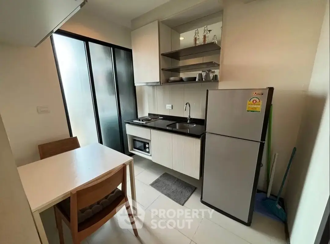 Modern compact kitchen with dining area, featuring sleek cabinetry and stainless steel appliances.