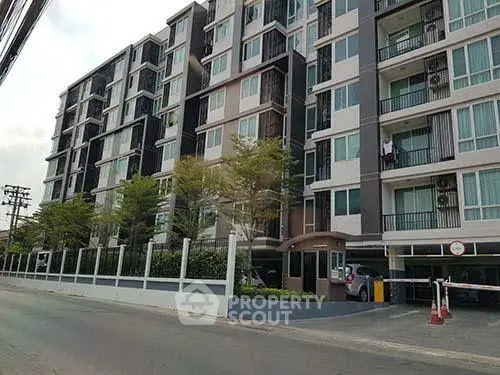 Modern multi-story apartment building with balconies and street view.