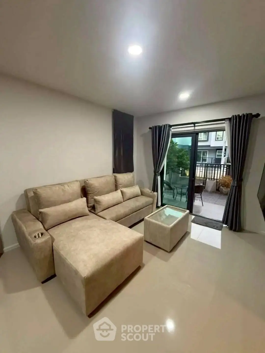 Modern living room with beige sofa and access to outdoor balcony in stylish apartment.