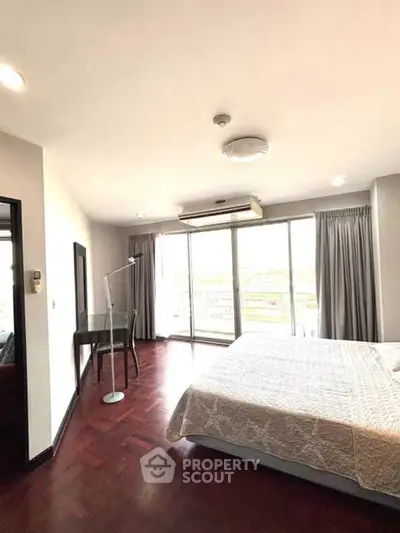Spacious bedroom with large windows and modern decor, offering a bright and airy ambiance.