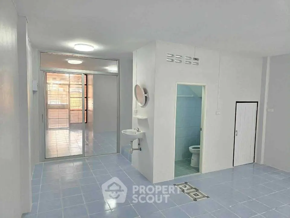 Spacious open-plan living area with blue tiled flooring and adjacent bathroom.