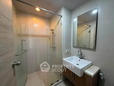 Modern bathroom with glass shower and sleek vanity in a contemporary apartment.