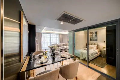 Luxurious open-plan living and dining area with elegant decor and a view into a cozy bedroom.