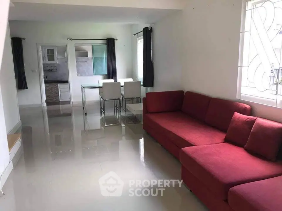 Spacious living room with modern red sofa and dining area, perfect for family gatherings.