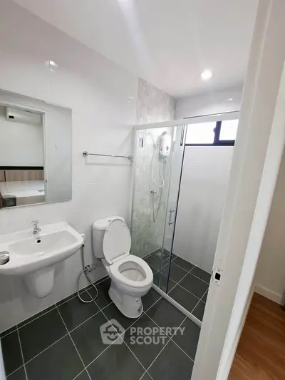Modern bathroom with glass shower and sleek fixtures in contemporary home.