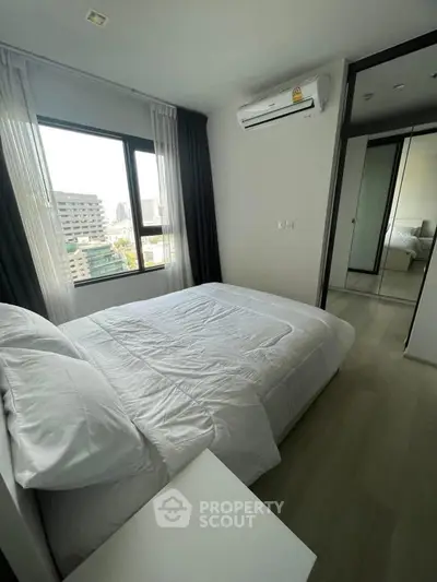 Modern bedroom with city view, featuring a comfortable bed and mirrored wardrobe.