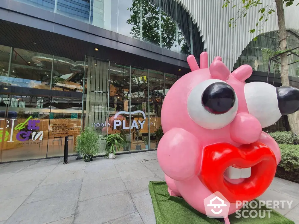 Modern commercial building entrance with unique pink sculpture and glass facade