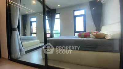 Modern bedroom with large windows and mirrored closet doors, offering a spacious and bright ambiance.