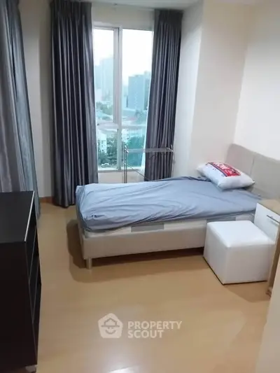 Cozy bedroom with city view, featuring a single bed and modern furnishings, perfect for urban living.