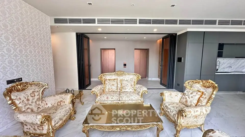 Luxurious living room with elegant gold-accented furniture and modern open kitchen layout.