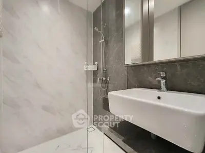 Modern bathroom with sleek design, featuring a glass shower and elegant sink.