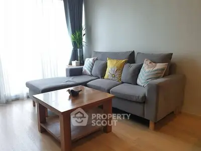 Modern living room with stylish gray sofa and wooden coffee table, bright natural light.