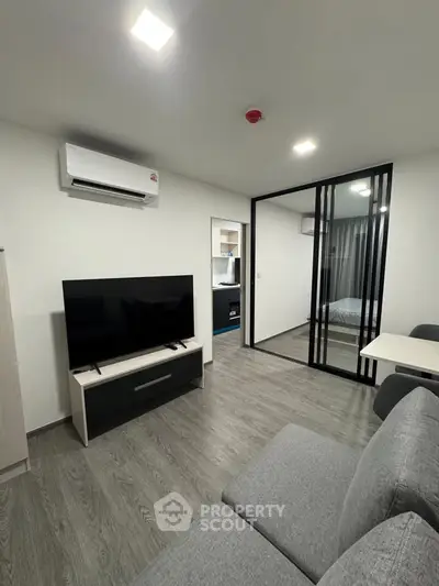 Modern living room with sleek glass partition and stylish furnishings in a contemporary apartment.