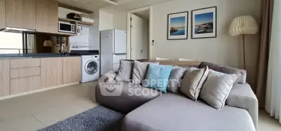 Modern living room with open kitchen, cozy sofa, and stylish decor in a contemporary apartment.