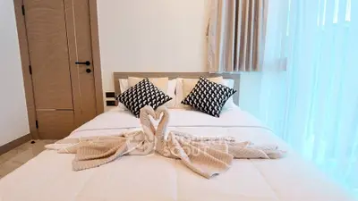 Luxurious bedroom with elegant decor and natural light, featuring stylish pillows and swan towel art.