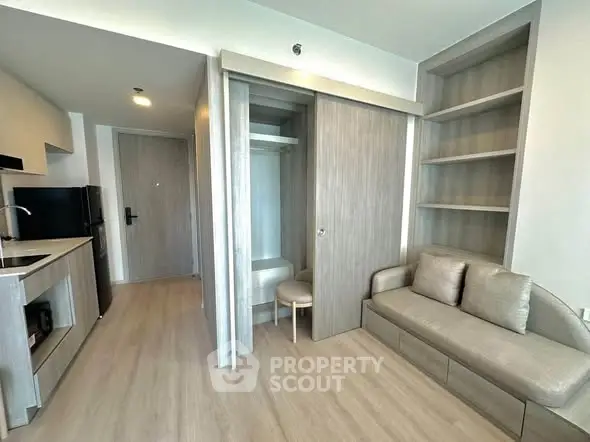 Modern studio apartment with sleek kitchen and cozy living area, featuring built-in storage and contemporary design.