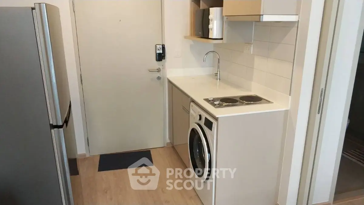 Compact modern kitchen with washing machine and electric stove in a cozy apartment.