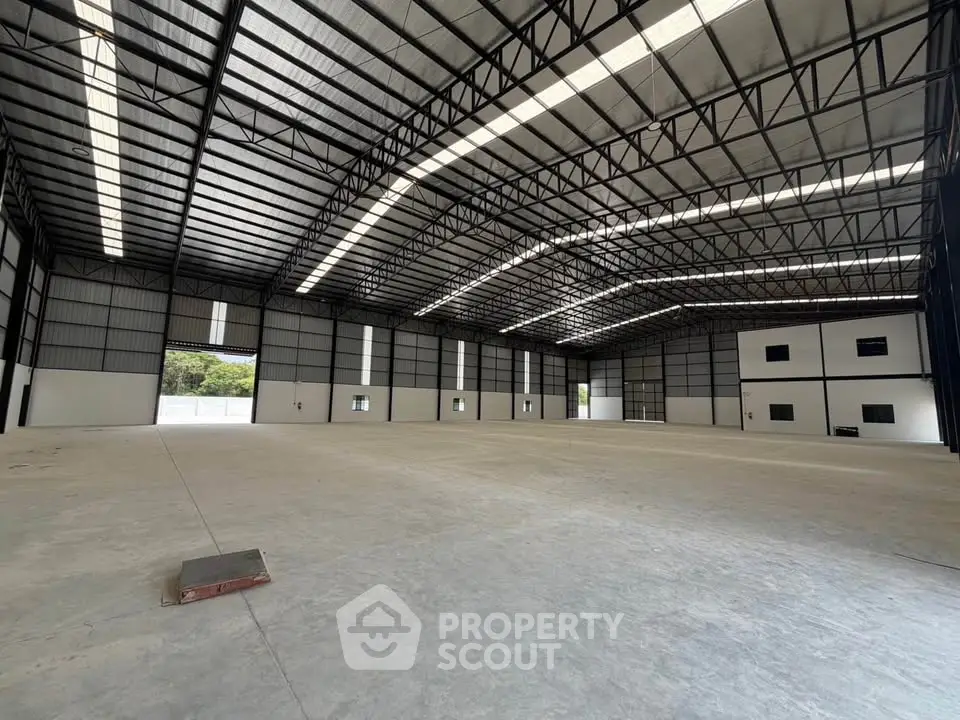 Spacious industrial warehouse with high ceilings and ample natural light, perfect for storage or manufacturing.
