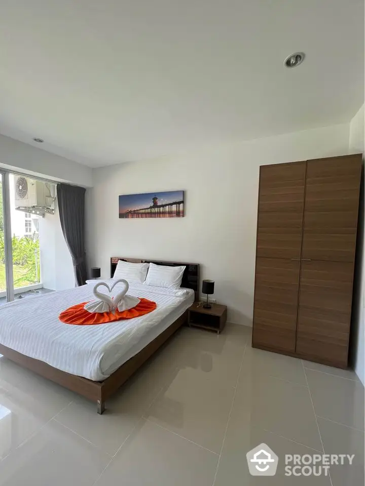 Modern bedroom with stylish decor and large window offering natural light.