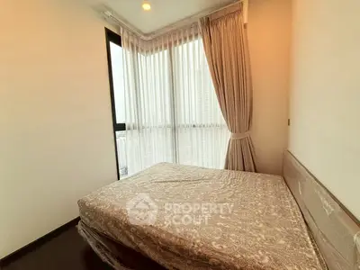Cozy bedroom with large windows and elegant curtains, offering a bright and inviting atmosphere.
