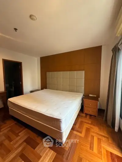 Spacious bedroom with wooden flooring and large bed in modern apartment