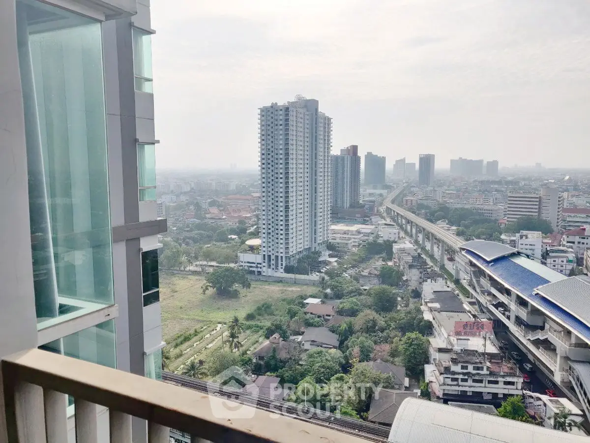 Stunning cityscape view from high-rise balcony overlooking urban skyline and transit line.