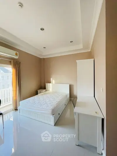 Spacious bedroom with natural light and modern white furniture, perfect for relaxation.