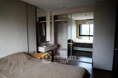 Modern bedroom with mirrored wardrobe and natural light from large window.