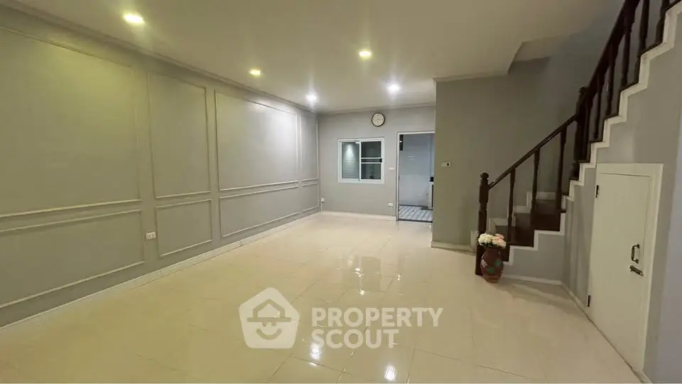 Spacious living room with elegant staircase and modern lighting, perfect for family gatherings.