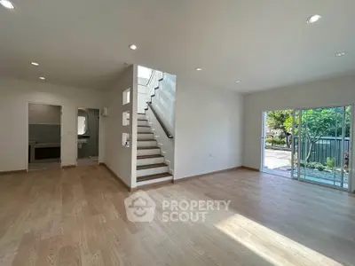 Spacious modern living room with wooden flooring and large windows opening to a garden view.