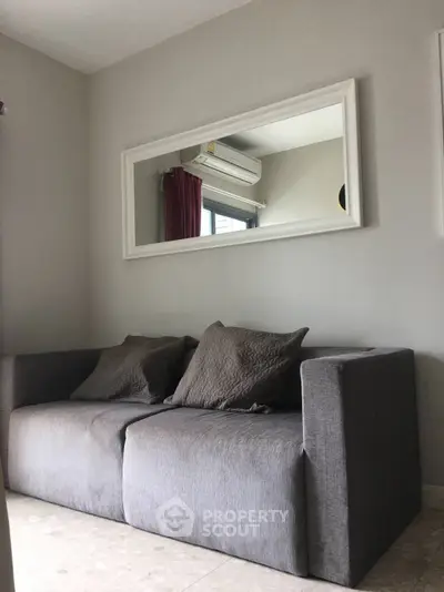 Cozy living room with modern gray sofa and wall-mounted mirror, perfect for relaxation.
