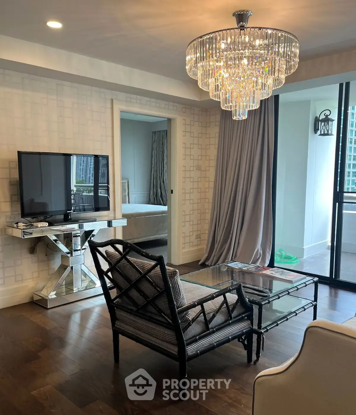 Luxurious living room with elegant chandelier and modern decor, featuring a spacious balcony view.