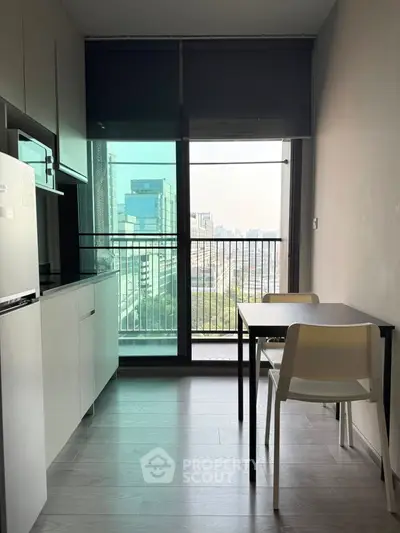 Modern kitchen with city view, sleek cabinetry, and dining area in a high-rise apartment.