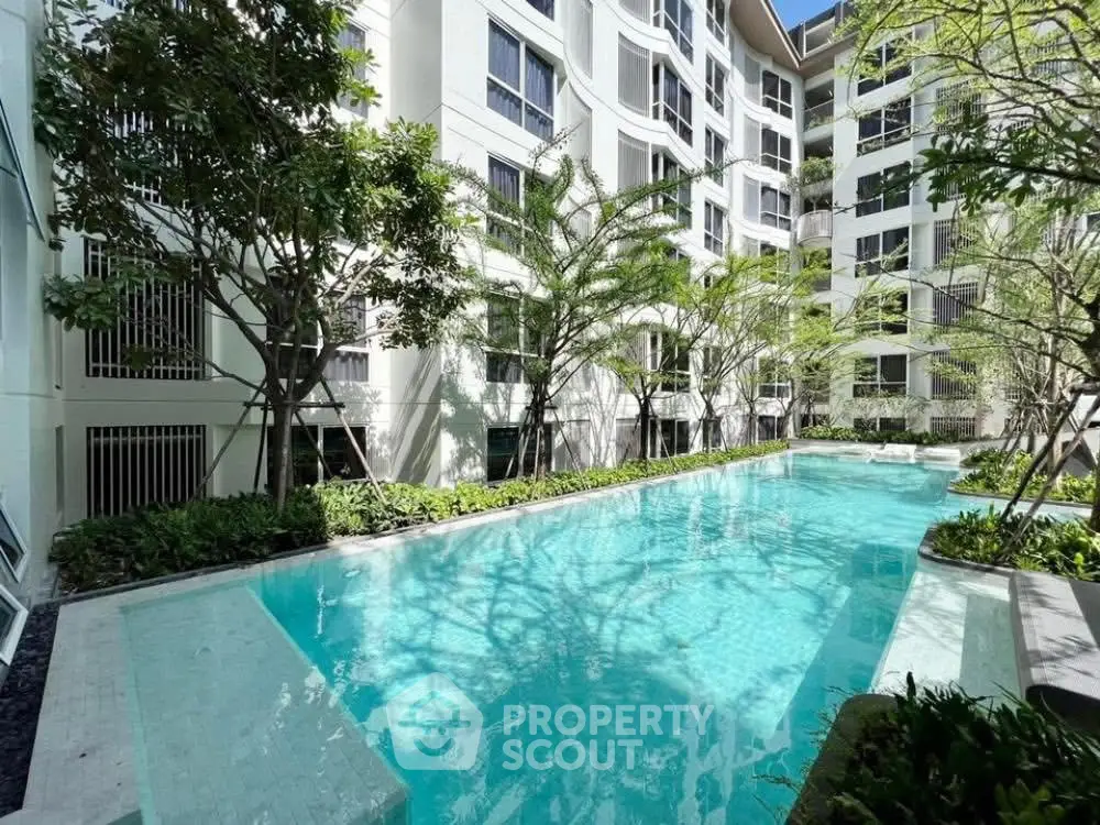 Luxurious residential building with serene pool and lush greenery, perfect for relaxation and leisure.