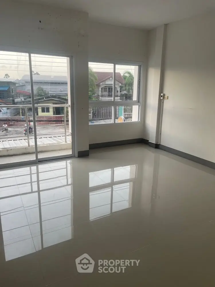 Spacious empty room with large windows and balcony access, offering ample natural light and urban views.