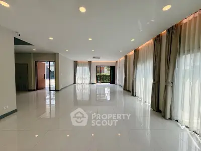 Spacious modern living room with large windows and elegant curtains, perfect for natural light lovers.