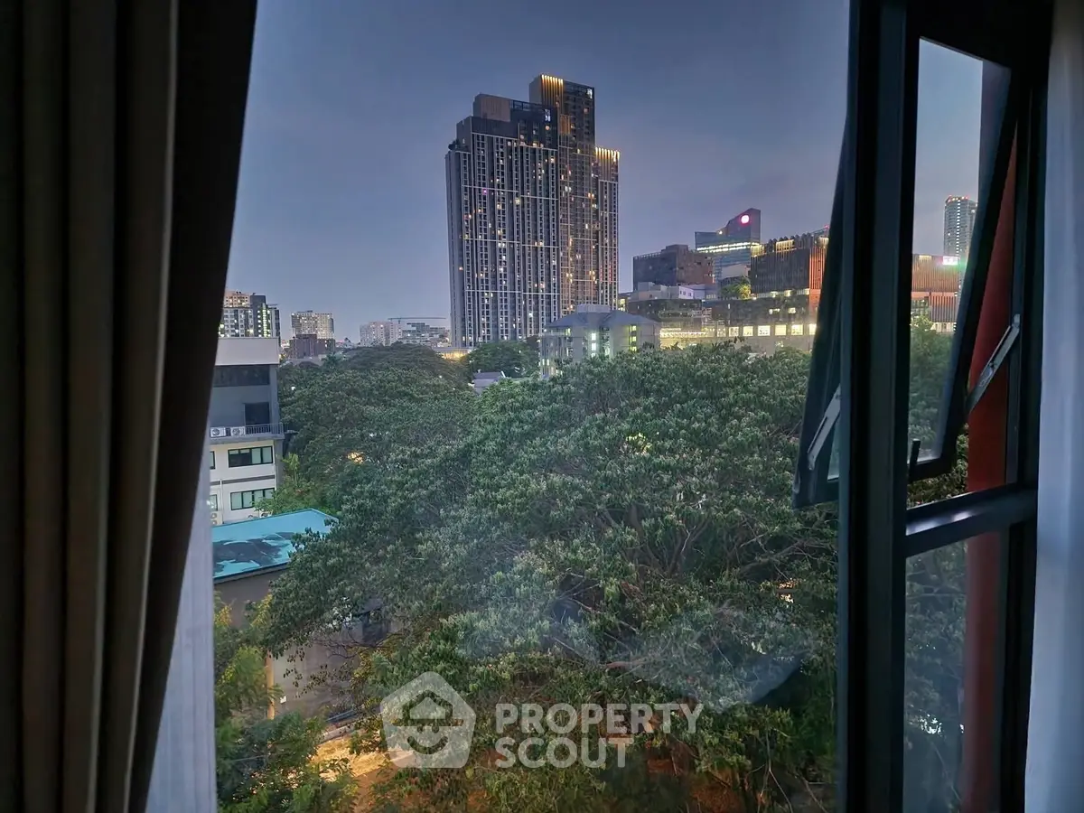 Stunning cityscape view from a window showcasing modern high-rise buildings and lush greenery.